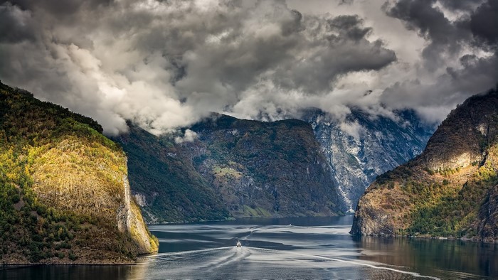Ship sailing through a Norwegian fjord with mountains