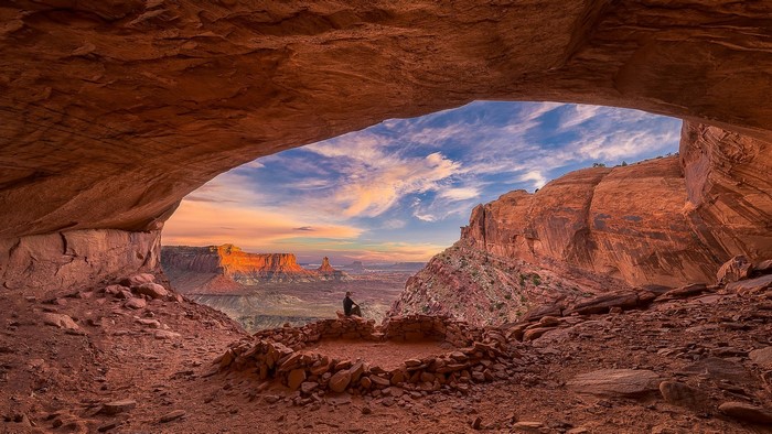 Person sitting in ancient ruins overlooking Canyonlands National Park