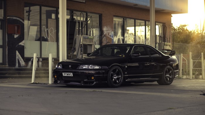 Black Nissan Skyline GT-R parked at abandoned gas station