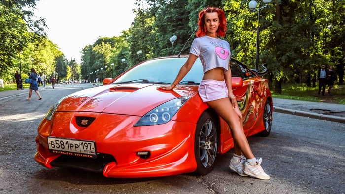 Woman posing with a red Toyota Celica