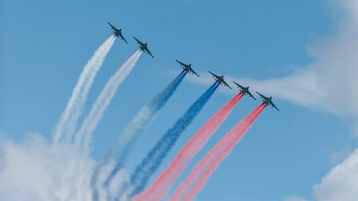 Six Su-25 aircraft flying in formation with colored smoke trails