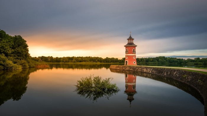 Red lighthouse on a lake at sunset