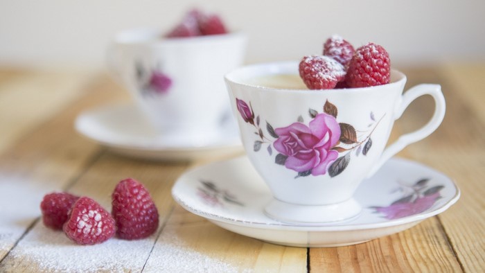 Two teacups with raspberries and powdered sugar