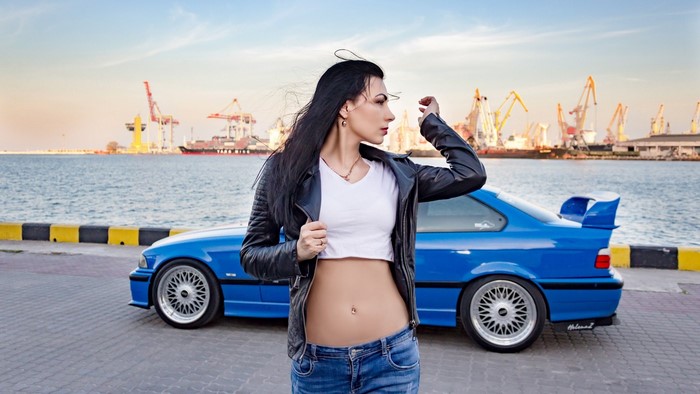 Woman in leather jacket and blue car at port