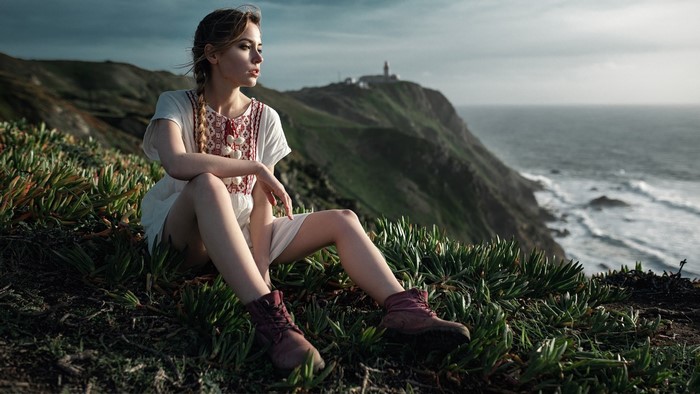 Girl sitting on a cliff overlooking the ocean