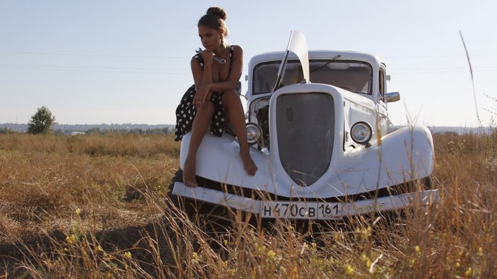 Girl in polka dot dress sitting on a retro car