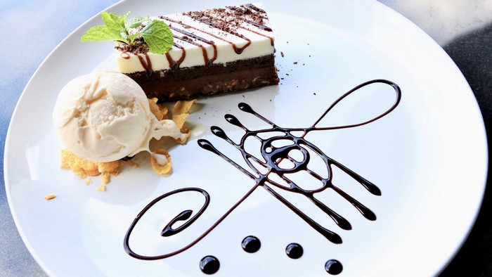 Slice of chocolate cake with ice cream and chocolate drizzle