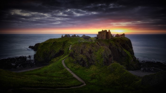 Dunnottar Castle ruins on a cliff at sunset