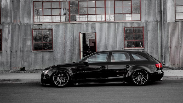 Black Audi A4 Avant parked by corrugated metal building