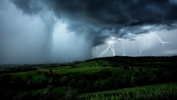 Storm with lightning over green landscape