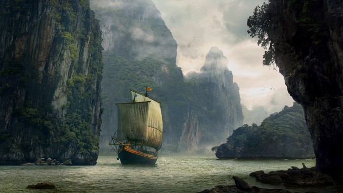 Sailboat navigating through rocky cliffs and mist