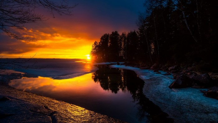Sunset over a frozen lake with trees