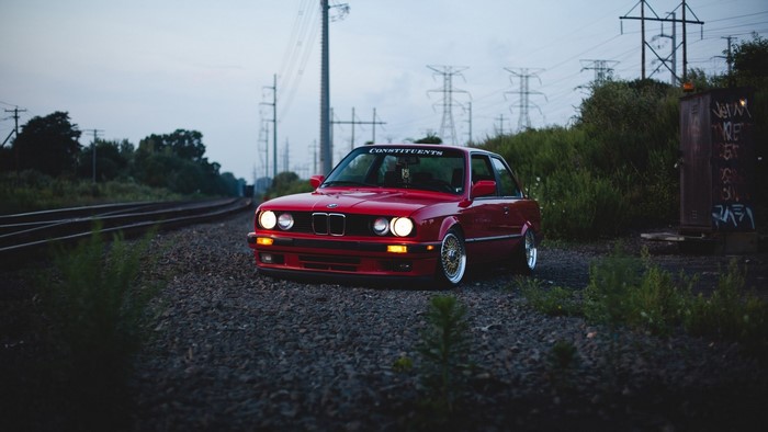 Red BMW E30 by train tracks