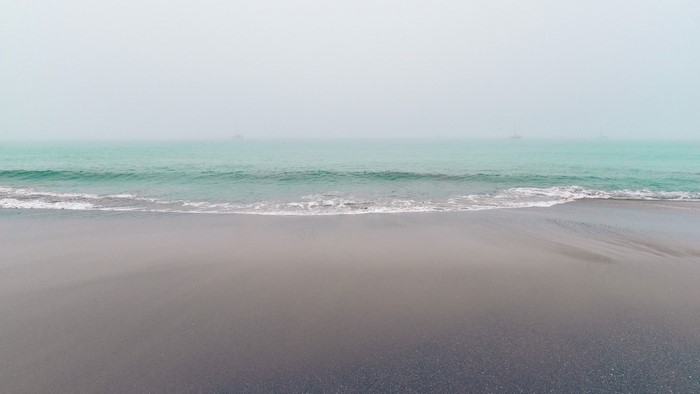 Foggy coast with turquoise water and boats