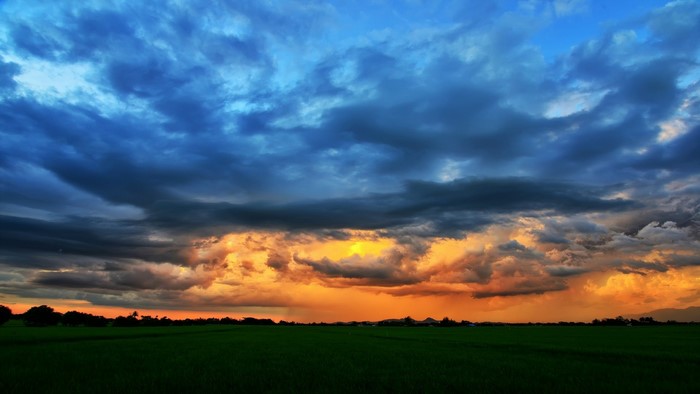 Dramatic sunset clouds over a green field