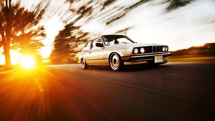 BMW E30 driving at sunset