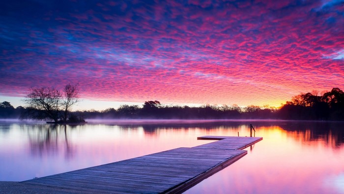Sunrise over lake with wooden pier in Hampshire, England