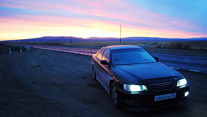 Black Toyota Chaser on a road at sunset