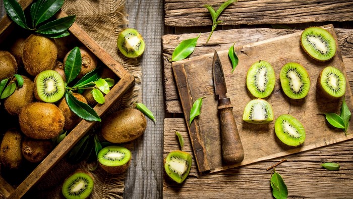 Whole and sliced kiwis on wooden boards