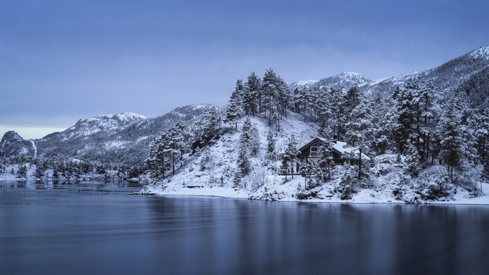 Snowy cabin by a lake in Norway