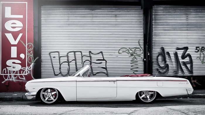 White Chevrolet Impala convertible parked by Levi's wall