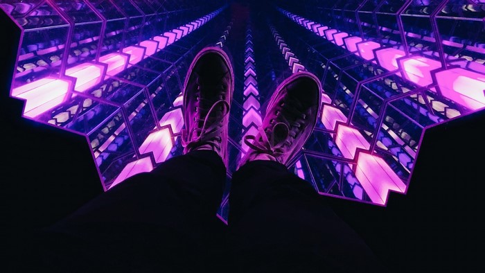Person's feet in sneakers in a purple infinity room