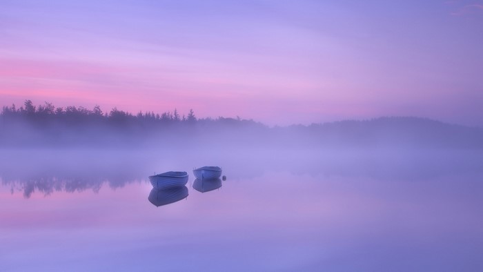 Two boats on a misty lake at sunrise