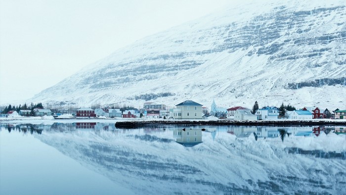 Snowy Icelandic village reflected in water