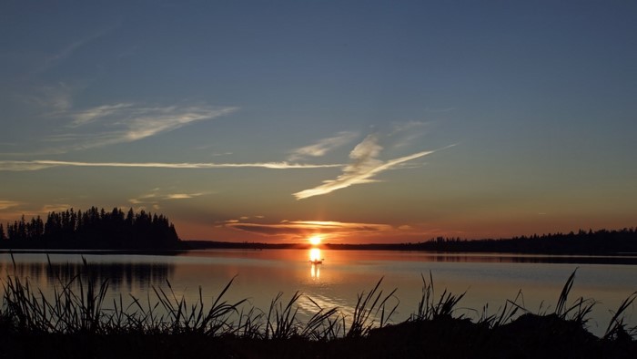Sunset over a lake with a boat