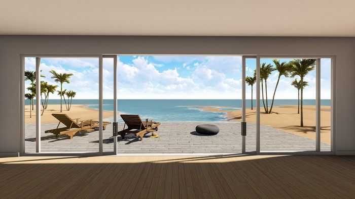 Sliding glass doors opening to a tropical beach with palm trees and lounge chairs
