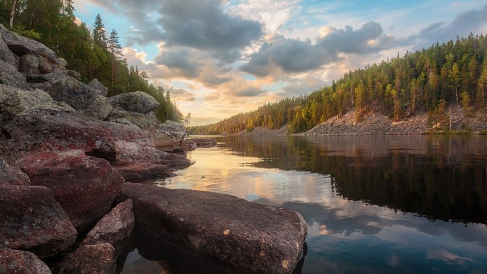 Rocky shore of a lake with forest and clouds