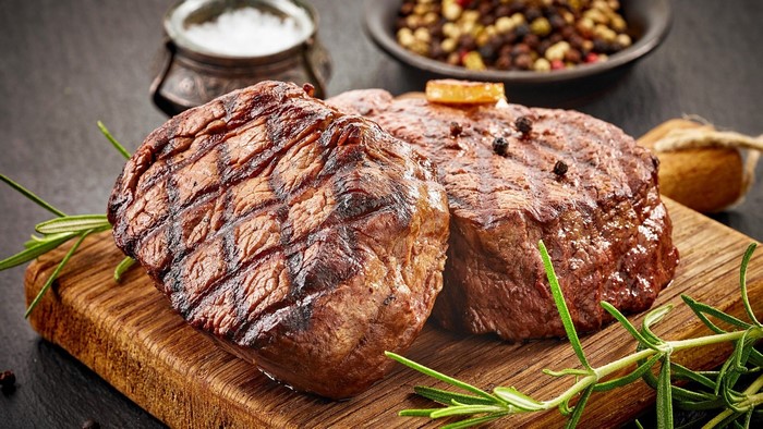 Two grilled beef steaks with rosemary and peppercorns