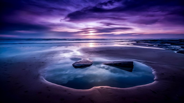 Purple sunset over a beach with tide pools