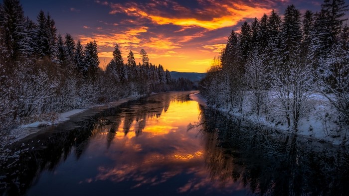 Winter river at sunset with snow-covered trees