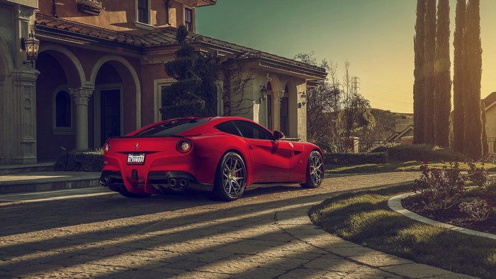 Red Ferrari F12 Berlinetta parked in front of a mansion