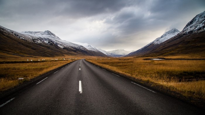 Road through a valley in Iceland with snow-capped mountains