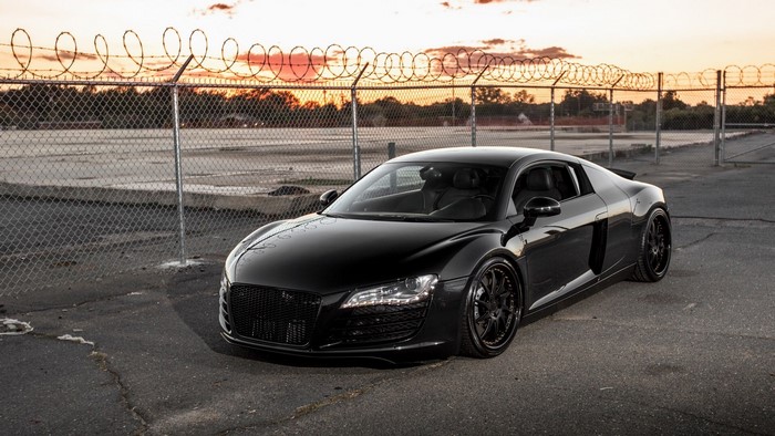 Black Audi R8 parked near a fence