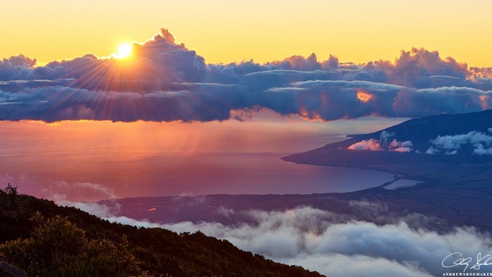 Sunrise over the ocean with clouds and mountains