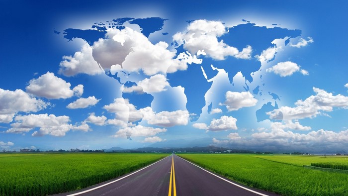 World map in the sky over a road and fields