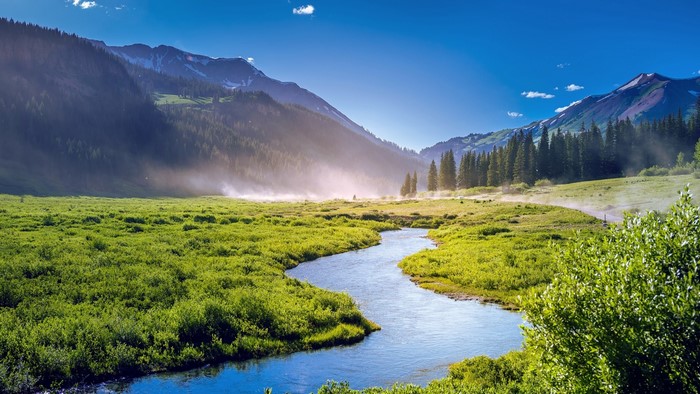 River flowing through a misty mountain meadow