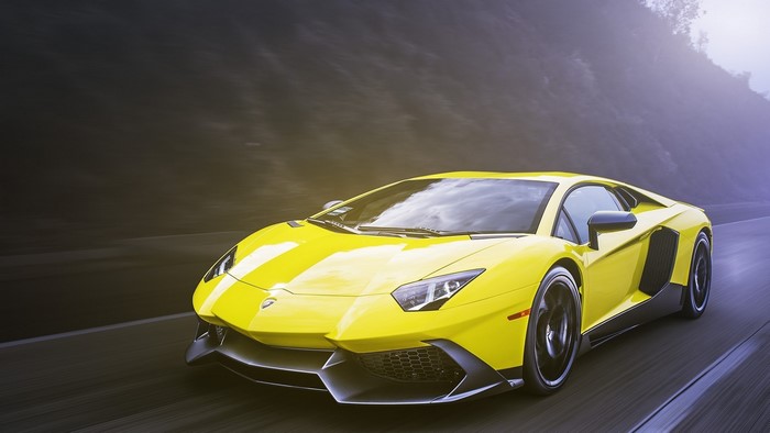 Yellow Lamborghini Aventador LP driving on a road