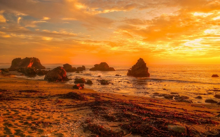 Sunset over rocky beach with ocean waves