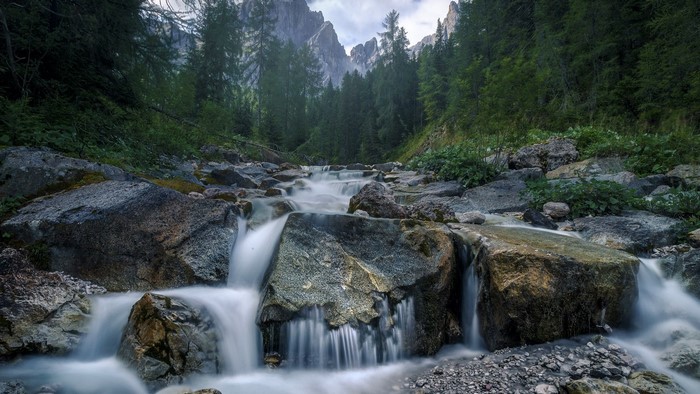 River flowing through a rocky forest with mountains