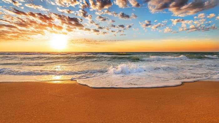 Sunset over the ocean with waves on the beach