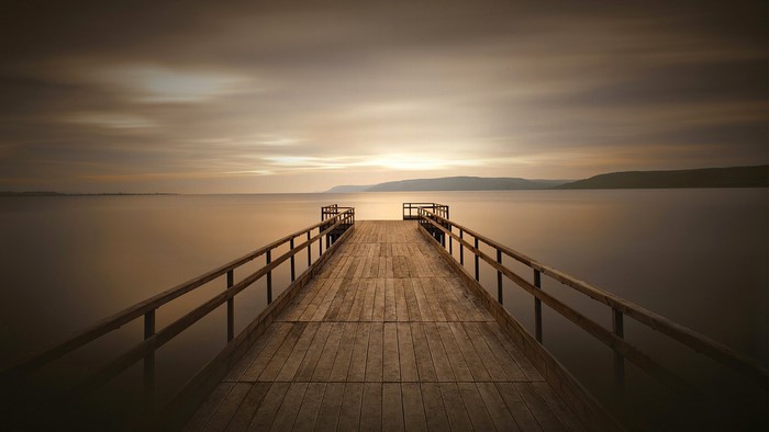 Wooden dock on a calm lake at sunset