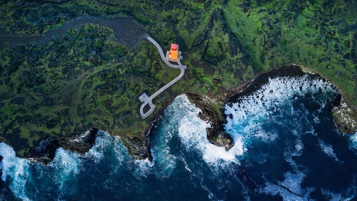 Svortuloft Lighthouse on a green cliff by the ocean