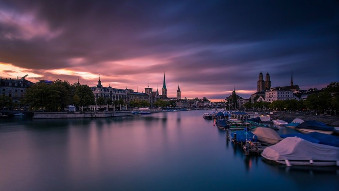 Zurich cityscape with river and boats at sunset