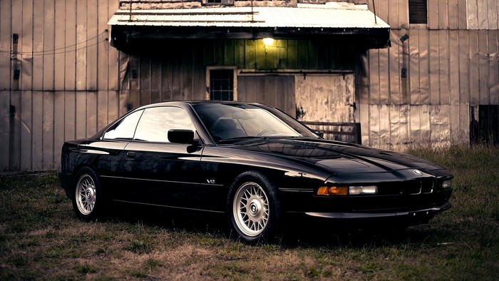 Black BMW 850i parked in front of a weathered building