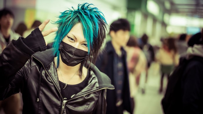 Person with blue and black hair wearing a mask and jacket