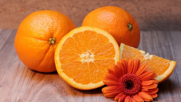 Oranges and a flower on a wooden surface